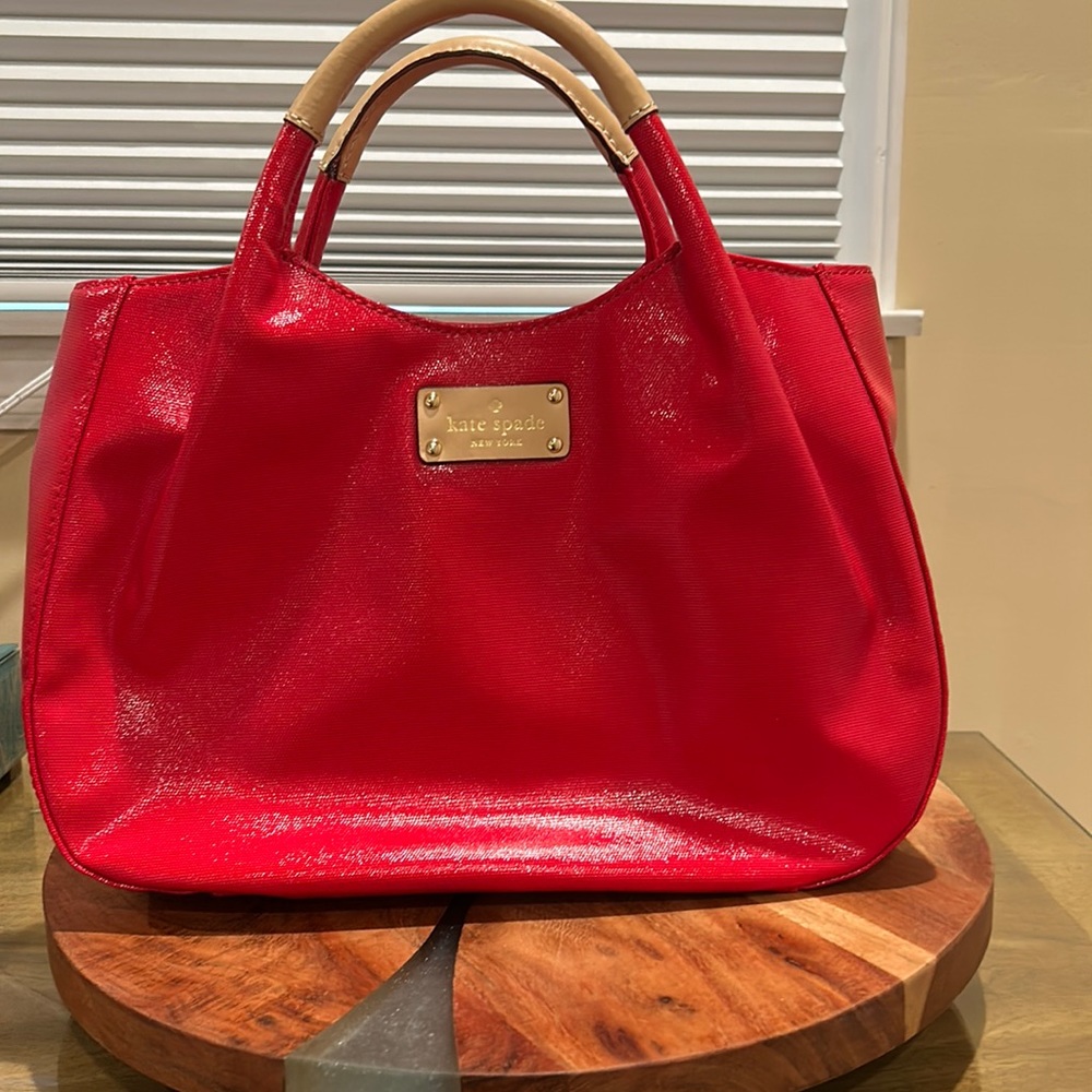 Kate Spade red shiny handbag. Light leather handles and matching leather tags.